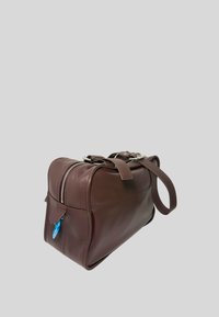 Borsa da viaggio in pelle marrone con una forma strutturata, cerniera argentata, doppi manici e un'etichetta decorativa blu sul lato.