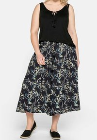 Černý bezramínkový top s detaily na zavázání; volné vzorované culotky v černé barvě s motivy bambusu v zelené, modré a krémové barvě; černé espadrilky.