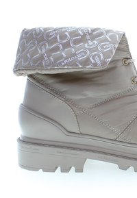 Stivale impermeabile beige con un bordo imbottito caratterizzato da un motivo ripetuto del logo. Suola spessa e strutturata con battistrada pronunciato per una migliore aderenza.