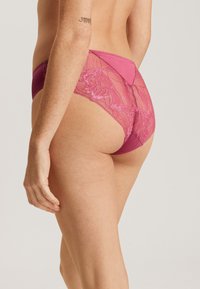 Bragas de encaje rosa con la parte trasera de encaje, un frente de tela sólida, intrincados detalles florales de encaje y un acabado suave a lo largo de los bordes.