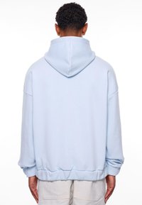 Hellblaue Over-size-Hoodie mit Kapuze und Kordelzug, gerippten Bündchen und einem gefütterten Saum. Weicher, glatter Stoff ohne sichtbare Muster.