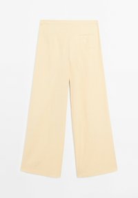 Pantalon beige à jambes larges avec taille haute et une seule poche arrière à fermeture par bouton, posé à plat sur un fond blanc.