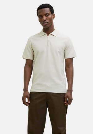Polo shirt beige chiaro con colletto e zip, caratterizzato da sottili righe orizzontali. Maniche corte e vestibilità rilassata.