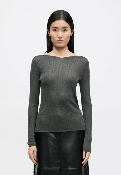 Γκρι ριπ πλεκτό πουλόβερ με μακρύ μανίκι και στρογγυλή λαιμόκοψη, εφαρμοστή σιλουέτα και υφή, σε συνδυασμό με μια μαύρη δερμάτινη φούστα.