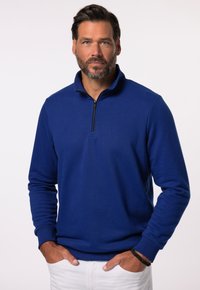 Blauer Half-Zip-Pullover aus weichem Stoff, mit langen Ärmeln und einem strukturierten Kragen sowie einem schwarzen Reißverschluss.