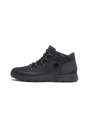 Baskets Timberland montantes noires avec fermeture à lacets, semelle texturée et logo de la marque sur le côté et le talon.