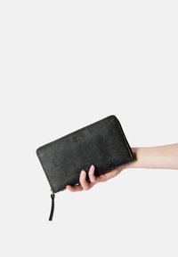 Black leather wallet with a smooth texture, zip closure, and a decorative tassel. Embossed logo on the front. Handheld presentation.