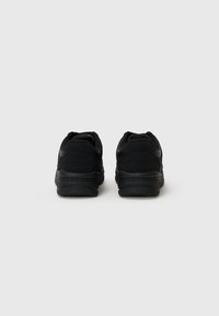 Black athletic shoes with a textured upper, cushioned soles, and a minimalist design. Padded collar and heel for added comfort.