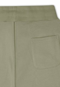 Green sweatpants featuring a ribbed elastic waistband, back pocket, and smooth textured fabric with a simple design.