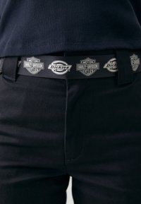 Juodas audinio diržas su pakartotiniais "Harley-Davidson" ir "Dickies" logotipais. Diržas turi lygią tekstūrą ir stačiakampį sagtį.