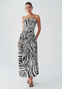 Axelbandslös maxiklänning i svart och vitt zebramönster med åtsittande överdel, texturerat tyg och sidofickor.