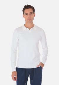Maglione bianco con maniche lunghe e collo a camicia. Realizzato in un tessuto a maglia liscio, presenta una silhouette aderente e un orlo a costine.