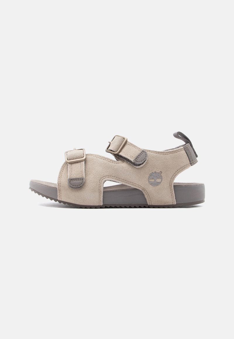 Μπεζ σουέτ σανδάλι με δύο ρυθμιζόμενους ιμάντες με αγκράφες, γκρι σόλα και θηλιά στην φτέρνα, με λογότυπο δέντρου στο πλάι.