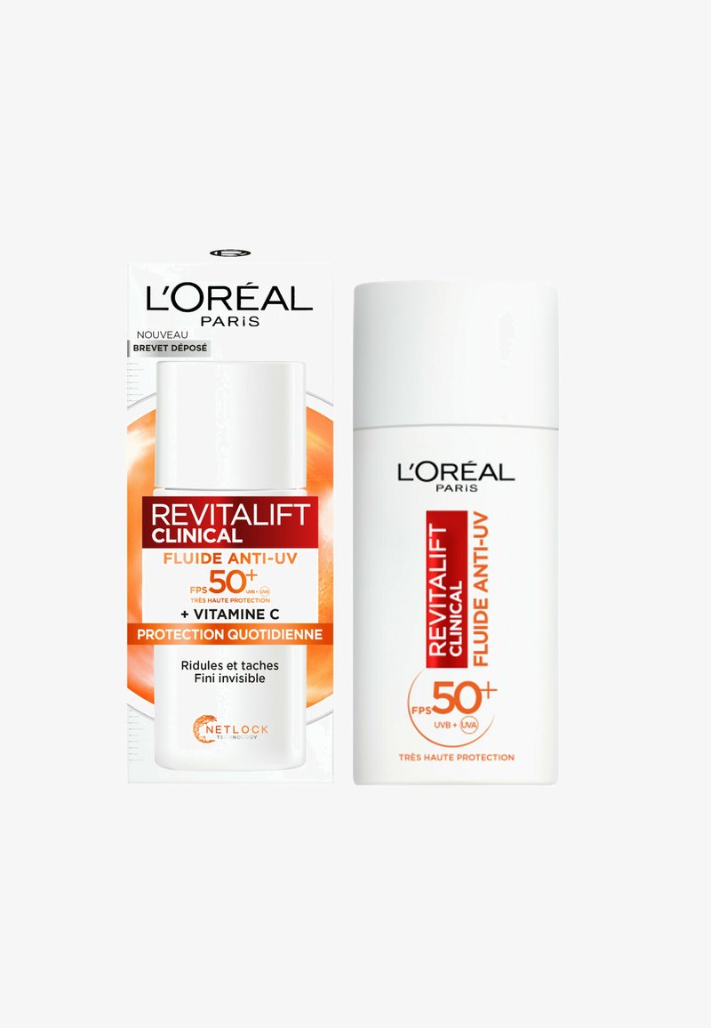 Le soin solaire L'Oréal Revitalift Clinical dans un flacon blanc, mettant en avant des accents orange. Contient un SPF 50+, de la vitamine C et des bienfaits anti-âge.