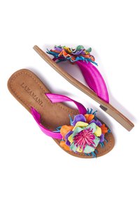 Las sandalias de dedo rosa presentan un colorido adorno floral con pétalos en capas de color verde, azul, amarillo, púrpura y naranja. Tira de imitación de piel.