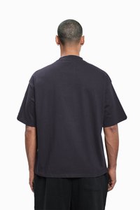Mørk marineblå t-skjorte med korte ermer, løs passform, rund hals og minimalistisk design, laget av lett bomullsstoff.