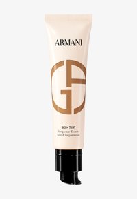 Beige tub av Armani Skin Tint med svart pumpmunstycke. Har varumärkeslogotyp i ljusbrunt, märkta "long-wear & care." Slät textur.