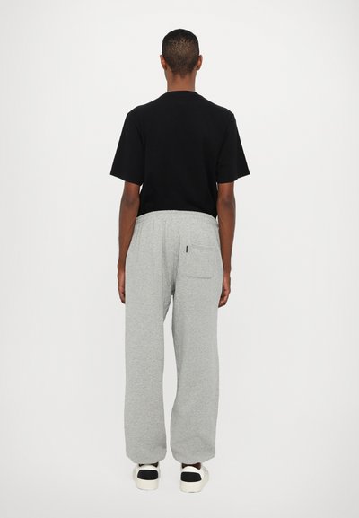 Black t-shirt with a crew neck, paired with gray sweatpants featuring an elastic waistband and side pocket. Casual, relaxed fit.