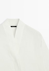 Hvid badekåbe med sjalskrave vist fladt, der viser den øverste front og Massimo Dutti-mærkelabel inden i halsudskæringen.