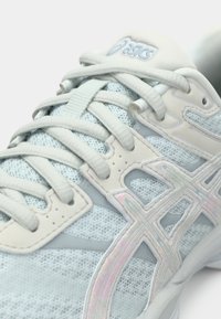 Zapatilla deportiva azul claro con parte superior de malla, tela texturizada y acentos reflectantes. Presenta cordones y un cuello acolchado para mayor comodidad.