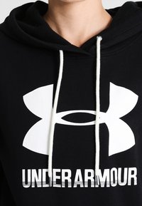 Czarna bawełniana bluza z kapturem z dużym białym logo Under Armour i białymi sznurkami. Gładka faktura, klasyczny design.