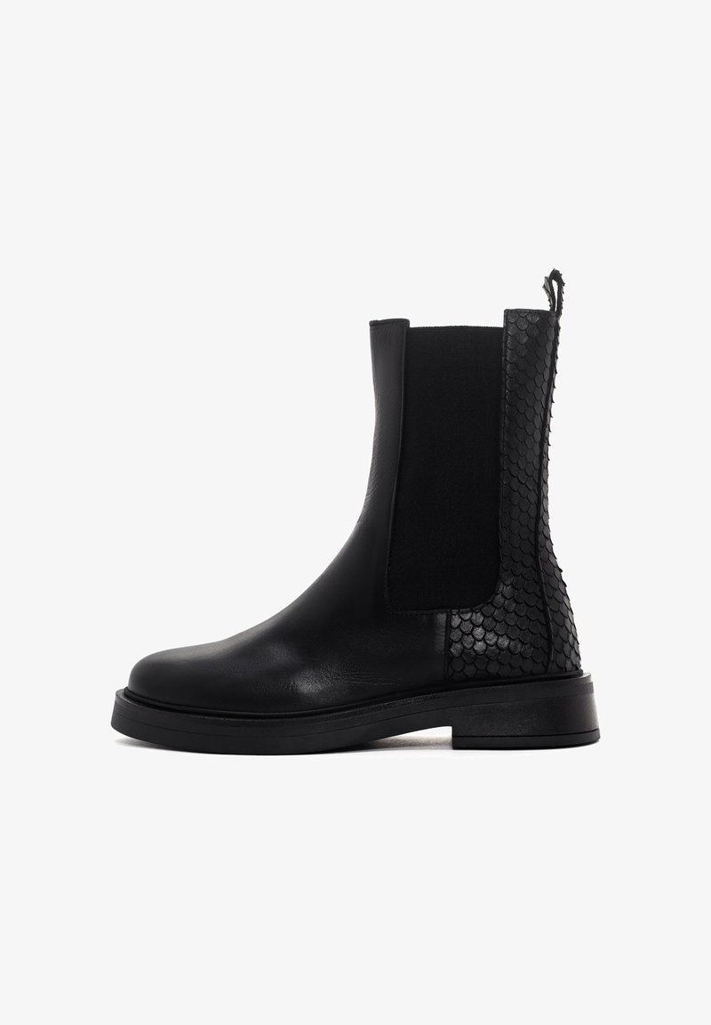 Botte noire en cuir mi-mollet avec des écailles texturées sur le talon et l'arrière, panneau latéral élastique, semelle épaisse et languette de traction en haut.