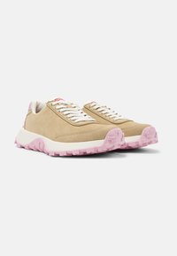 Beige suede sports shoes with white laces, pink rubber outsole, and a textured sole. Features a subtle logo detail on the tongue.