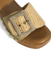 Bruine open teen sandaal met een brede geweven stroband, versierd met een gesp met rhinestones en gouden studs langs de zijkant.