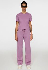 Lichtpaars sportoutfit bestaande uit een T-shirt met korte mouwen en een broek met trekkoord, gemaakt van zachte stof met een ontspannen pasvorm.