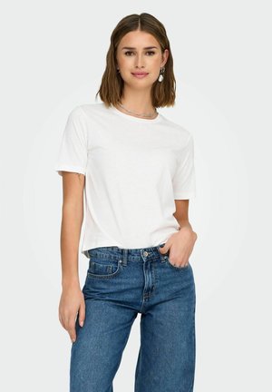 Maglietta bianca in cotone con maniche corte e scollo rotondo, abbinata a jeans in denim blu a vita alta. Design semplice, senza motivi visibili.