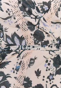 Robe portefeuille florale en tissu doux, arborant des motifs vert foncé et lavande, accentuée par une délicate bordure en dentelle beige le long de l'avant.