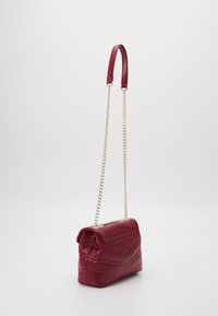 Borsa a tracolla in pelle rossa con design trapuntato, dotata di una catena d'oro e chiusura a patta superiore. Texture liscia con dettagli di cuciture geometriche.