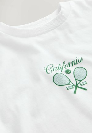 T-shirt bianco in cotone con stampa verde di due racchette da tennis e testo "California EST. 1987", con colletto girocollo classico.