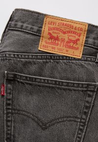 Poche grise de jean Levi's avec étiquette en cuir marron Levi Strauss & Co. montrant le logo, la taille et les détails du style.