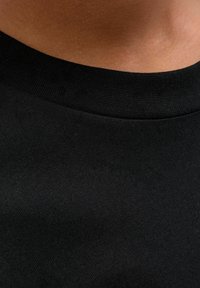 Czarna koszulka z tkaniny o gładkim wykończeniu, z prążkowanym okrągłym dekoltem, o jednolitym kolorze, prezentująca prosty i minimalistyczny design.