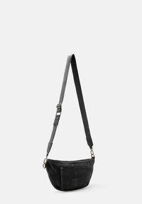 Schwarze Schultertasche aus weichem Stoff, mit runder Form, verstellbarem Tragegurt, Vorderfach mit Reißverschluss und minimalen Hardware-Details.