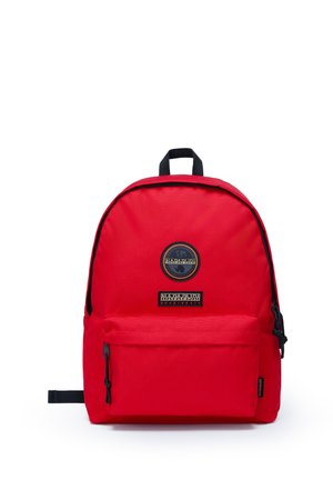 Zaino in tessuto rosso con silhouette arrotondata, dotato di una tasca frontale con zip, patch del logo e dettagli neri su spallacci e zip.