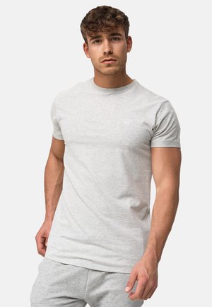 T-shirt gris clair à manches courtes en tissu doux et lisse, avec un col rond et un petit logo sur la poitrine gauche.