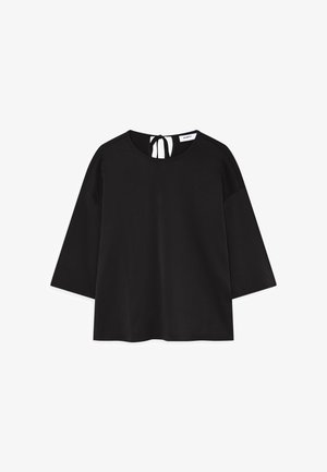 Musta toppi, jossa on pyöreä kaula-aukko, kolmanneksen pituiset hihat ja auki oleva selkä, jossa on nauhakiinnitys. Silkkinen, kevyt kangas. Yksinkertainen muotoilu.