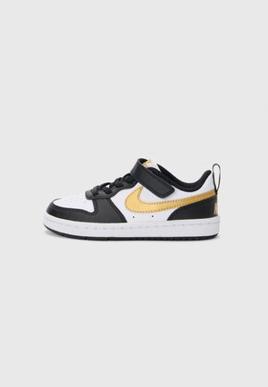 Baskets noires, blanches et dorées avec une tige en cuir texturé et synthétique, une sangle Velcro et une semelle en caoutchouc. Présente un design swoosh proéminent.