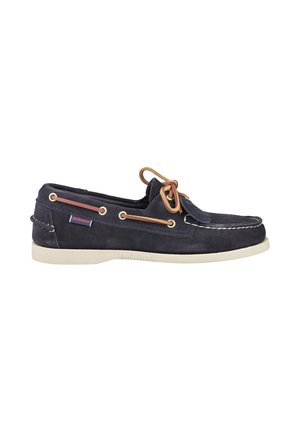 Navy blue suede boat shoe with white sole, tan leather laces threaded through brass eyelets, and side tag labeled Sebago.