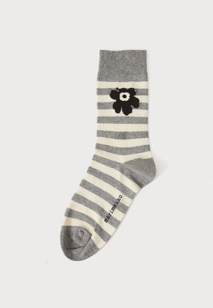 Gestreifte graue und cremefarbene Socke mit einem blumenförmigen Design in Schwarz, ausgestattet mit einem gerippten oberen Rand und einem verstärkten Zehenbereich. Markenname seitlich aufgedruckt.