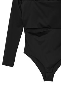Costume intero nero a maniche lunghe con gamba alta e una piccola chiusura nella zona inguinale.