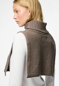 Ruskea neuleliivi korkealla ribbireunalla. Rakennetta omaava malli avoimilla sivuilla, käytetään valkoisen pitkähihaisen paidan päällä.