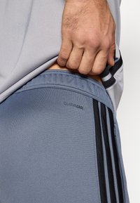 Αθλητικό σορτς σε μπλε ύφασμα με λεία υφή, με λογότυπο "CLIMACOOL", μαύρες ρίγες στα πλαϊνά και άνετη εφαρμογή.