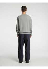 Grå genser med lange ermer, ribbet kant og rund hals. Kombinert med løstsittende marineblå bukser. Enkel, moderne design.