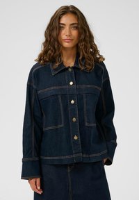 Dunkelblaue Jeansjacke mit Knopfleiste, großen Brusttaschen und kontrastierendem Nähen. Verfügt über einen klassischen Kragen und eine lässige Passform.