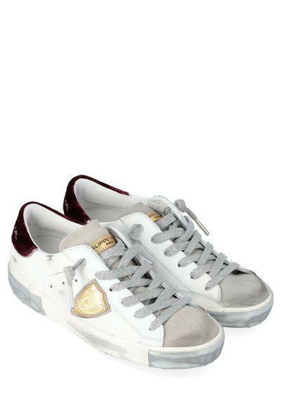 Sneaker bianche in pelle con dettagli in suede grigio e accenti metallici dorati, dotate di lacci grigi e rifiniture in velluto borgogna sul tallone. Suola in gomma trasparente.