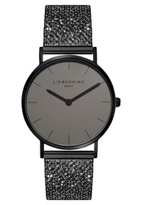 Ronde horloge met een grijze wijzerplaat, zwarte uurmarkeringen en een gestructureerde zwarte glittersband. De afwerking is stijlvol, met een eenvoudig ontwerp en donkere accenten.