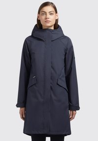 Navy waterproof parka with a high collar, zip front, side pockets, and buttoned cuffs. Smooth, slightly shiny fabric with a relaxed fit.